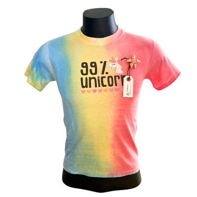 A multi-colored pastel tie-dye t-shirt with vertical yellow, pink, and blue stripes. It features the printed text "99% unicorn" in a playful font with a tiny unicorn head icon. A price or product tag is hanging from the collar.