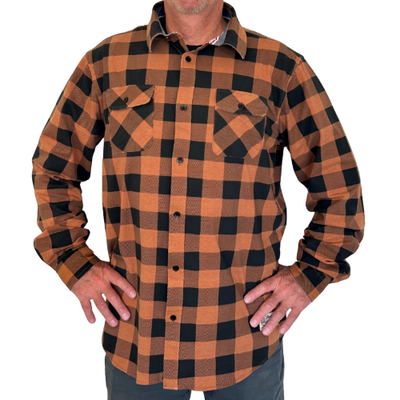 A man wearing an orange and black buffalo check plaid flannel shirt with long sleeves and two button-down chest pockets.